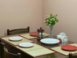 a table with plates and a vase of flowers on it at Lilia's Cozy Duplex In The City Center in Yerevan +25 photos