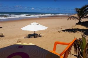 an umbrella and chairs on a beach with the ocean at Sossego em Imbassaí in Mata de Sao Joao