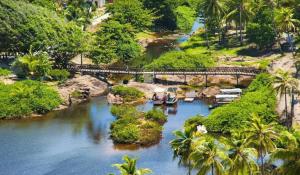 a bridge over a river with boats on it at Sossego em Imbassaí in Mata de Sao Joao