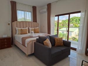 a bedroom with a bed and a couch and a window at Hermosa villa familiar cucu's home beach in Río San Juan