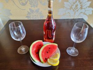 eine Flasche Wein, ein Teller Obst und zwei Weingläser in der Unterkunft Royal Beach hotel Apartment Pool Sea B in Sonnenstrand