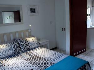 a bedroom with a bed with blue pillows and a mirror at Sea Why in Natureʼs Valley