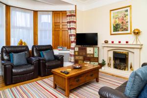a living room with leather furniture and a fireplace at Luxury 4BR, Free Parking, Near Beach, Sleeps 8 in Edinburgh