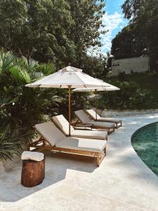 a group of lounge chairs and an umbrella next to a pool at Hotel Banyan Doradal in Puerto Triunfo