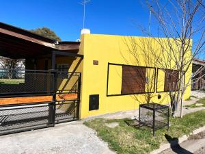 a yellow house with a black fence in front of it at El cóndor in Balneario El Condor