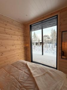 a bedroom with a bed and a large window at Modern VillaJoenhelmi with jacuzzi and sauna in Kuusamo