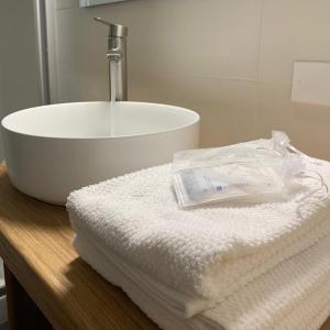 ein Badezimmer mit einem Waschbecken und Handtüchern auf der Theke in der Unterkunft Appartamento 21 - Smart Apartment nel centro di Segusino, vicino le colline del Prosecco in Sequsino