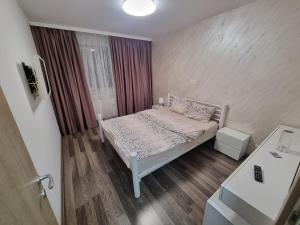 a small bedroom with a bed and a window at Ezzely apartment ParkLake in Bucharest
