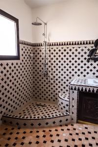 a bathroom with a shower with a black and white pattern at Dar Lily, villa familiale avec piscine et services in Skoura