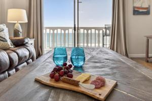 een snijplank met wijnglazen en kaas op een tafel bij Ormond Beach Paradise - Steps from no-drive beach in Ormond Beach