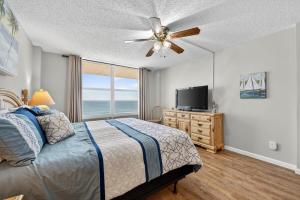 een slaapkamer met een bed, een plafondventilator en een televisie bij Ormond Beach Paradise - Steps from no-drive beach in Ormond Beach