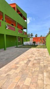 un gran edificio verde con una acera delante de él en Portal da Felicidade, en Maragogi