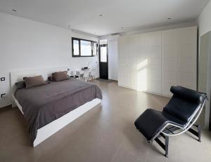 ein Schlafzimmer mit einem Bett und einem Stuhl darin in der Unterkunft Casa Blanca - Villa à Teguise avec piscine privée in Teguise + 28 Fotos