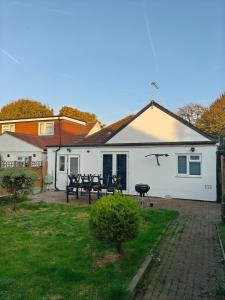 ein weißes Haus mit Grill im Hof in der Unterkunft Spacious 3-Bed Detached Home in London-Greenford in Northolt