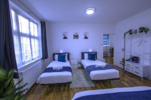 zwei Betten in einem Zimmer mit zwei Fenstern in der Unterkunft Spacious 3-Bed Detached Home in London-Greenford in Northolt