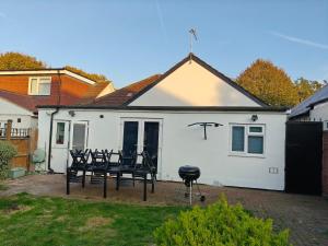 ein weißes Haus mit Stühlen und einem Grill im Hof in der Unterkunft Spacious 3-Bed Detached Home in London-Greenford in Northolt