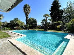 a swimming pool in a backyard with palm trees at Chez castagnet in Assat +30 photos
