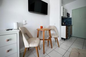 a small table with two chairs and a tv on a wall at Green Sea Studio in Rethymno