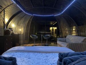 Un dormitorio con una cama y una sala de estar con un sofá. en Dôme du puits avec jacuzzi et sauna privatif, en Havinnes