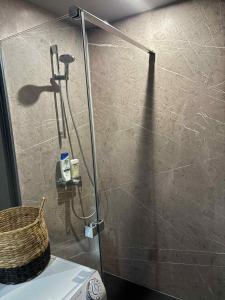 Un baño con ducha y un cesto sobre el inodoro. en Dôme du puits avec jacuzzi et sauna privatif, en Havinnes