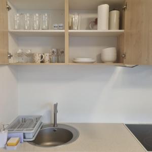 a kitchen counter with a sink and shelves with dishes at Juuli apartament in Kuressaare