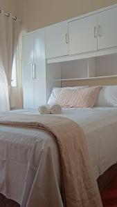 ein weißes Bett mit zwei Handtüchern darauf in der Unterkunft Quarto ao lado da praça da Liberdade in Belo Horizonte