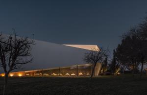 新蒙特莫尔L'AND Vineyards - Relais & Châteaux的夜晚有大玻璃幕墙的建筑