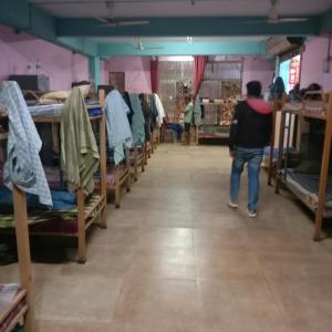 a man walking through a room filled with bunk beds at V R S Dormitory in Hubli