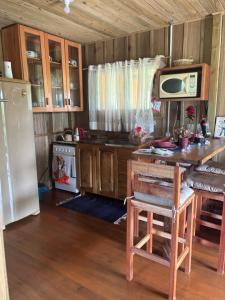 cocina con mesa, microondas y nevera en Pousada dos Sonhos - Casa Goiabeira, en Timbe do Sul