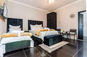 a bedroom with two beds and a table and chairs at WinHaven Guest House in Randfontein