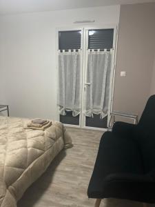 um quarto com uma cama e duas janelas com cortinas em Petit studio attenant à la maison em Saint-Agnant