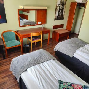 a room with two beds and a desk and a mirror at Highway Hotel in Härnösand