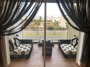a room with two couches and a large window at Apartment in residence CASABAY in Sidi Rahal