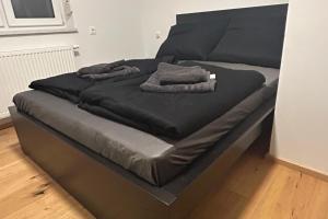 ein schwarzes Bett mit zwei Kissen darüber in der Unterkunft Cozy City Center Designer Apartment for 9 People in Wiener Neustadt