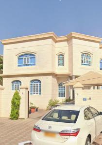 Un coche blanco aparcado delante de una casa en Moon hostel, en Seeb