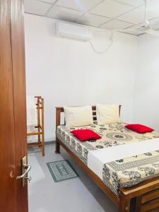 a bedroom with a bed with red pillows on it at Coastal breezy bangalow in Weligama