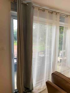 a window with white curtains in a living room at Grand studio cosy avec terrasse in Joue-les-Tours