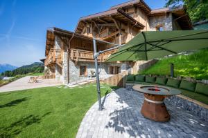 a table with an umbrella in front of a house at ULTIMATE Les Gets Luxury - Above the Clouds with Sauna, Pool etc - Mansion Ensolielle for 15 in Les Gets