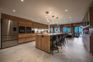 a kitchen with wooden cabinets and a bar with bar stools at ULTIMATE Les Gets Luxury - Above the Clouds with Sauna, Pool etc - Mansion Ensolielle for 15 in Les Gets