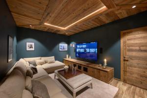 a living room with a couch and a tv at ULTIMATE Les Gets Luxury - Above the Clouds with Sauna, Pool etc - Mansion Ensolielle for 15 in Les Gets