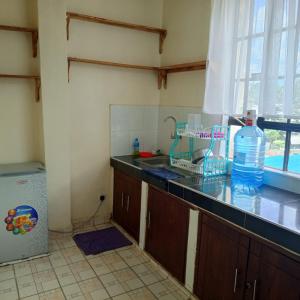 Amani -Zuriel homes 2 Bedroom Apartment في Kakamega: مطبخ مع حوض وزجاجة مياه على المنضدة