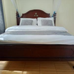 Amani -Zuriel homes 2 Bedroom Apartment في Kakamega: سرير عليه ملاءات ووسائد بيضاء