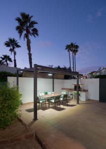 d'une terrasse avec une table, des chaises et des palmiers. dans l'établissement Villa Maspalomas Golf Court, à Maspalomas