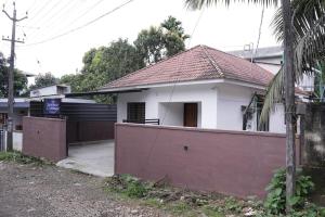 une maison blanche avec une clôture devant dans l'établissement Serene Cottage - Home away from Home, à Vythiri