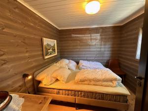 ein Bett in einem Zimmer mit einer Holzwand in der Unterkunft Modern Cozy Cabin Near Langsua National Park in Heggenes + 21 Fotos
