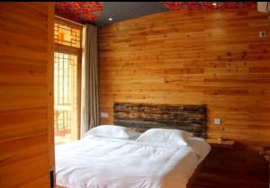 a bedroom with a bed in a wooden wall at Xiangtule Inn in Xinglong