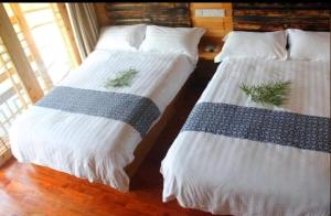 two beds sitting next to each other in a room at Xiangtule Inn in Xinglong