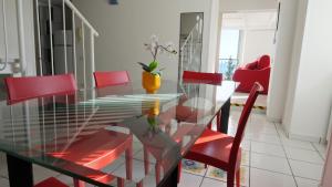 a glass dining room table with red chairs and a vase at RESIDENCE SOLARIDE apartments, FREE PRIVATE PARKING WITH VIDEOSURVELLIANCE and SHUTTLE SERVICE in Salerno