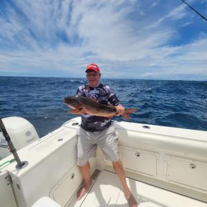 un homme tenant un gros poisson dans un bateau dans l'établissement Fishon Panama Lodge, à Boca Chica