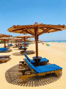 a beach with blue lounge chairs and umbrellas at La Cabana Beach Hotel Ain Sokhna in Ain Sokhna